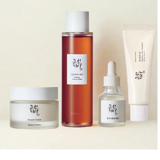Beauty of Joseon skincare essentials collection featuring Dynasty Cream in a frosted jar, Ginseng Essence Water in a tall amber bottle, Glow Serum in a dropper bottle, and Relief Sun SPF cream in a soft tube, arranged neatly on a beige background